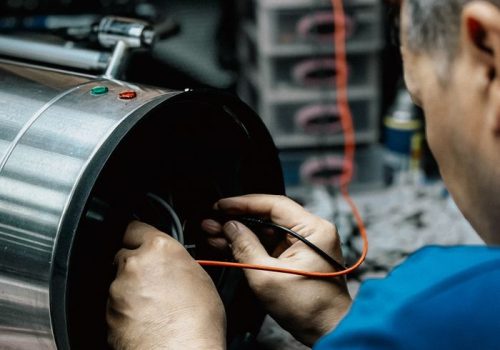 Professional technician examining and repairing industrial machinery in a workshop.