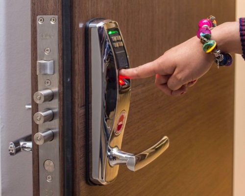 A hand using fingerprint access on a digital security door lock, enhancing safety.